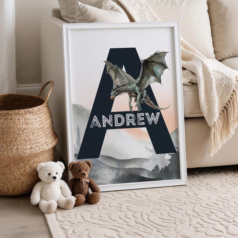 May include: Framed art print featuring a teal dragon over a navy blue letter "A" with the name "ANDREW" in white. The background shows a mountain landscape with a peach and gray color palette. A white frame surrounds the artwork.