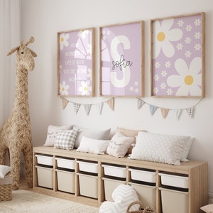 May include: Three framed prints with a purple background and white daisy flowers. The middle print has the name "Sofia" in black cursive writing. The left print has the text "How wonderful life is now you're in the world".
