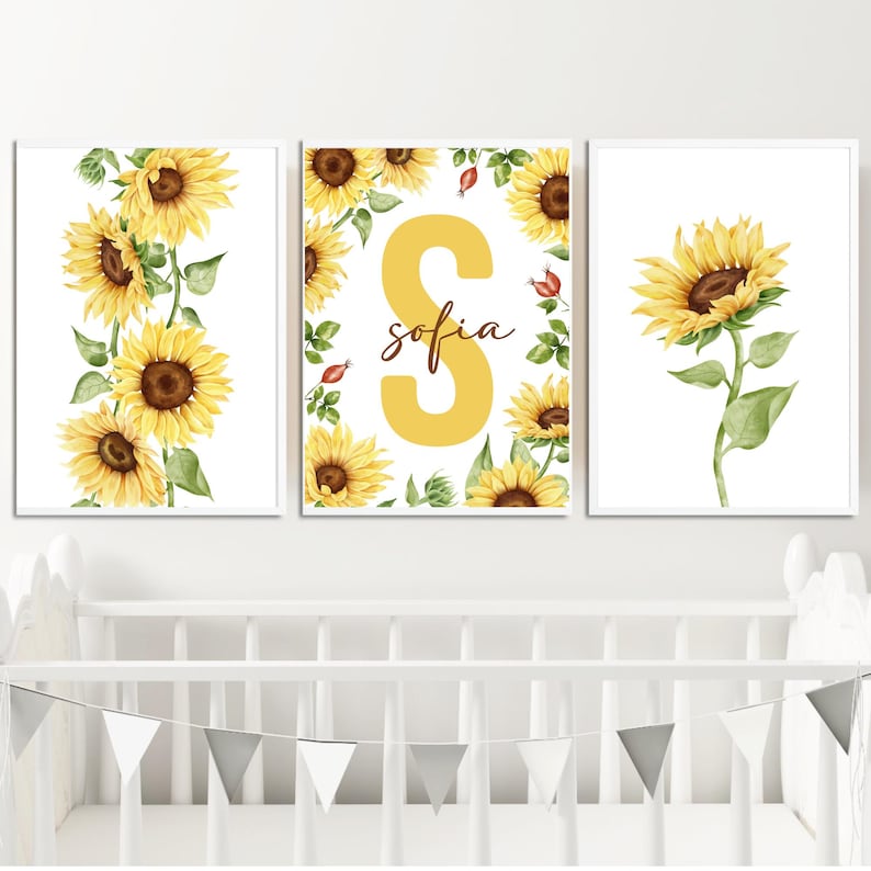 May include: Three framed prints with a sunflower theme. The center print features a large yellow letter "S" with the name "sofia" written in brown script. The left and right prints feature yellow sunflowers with green leaves on a white background.