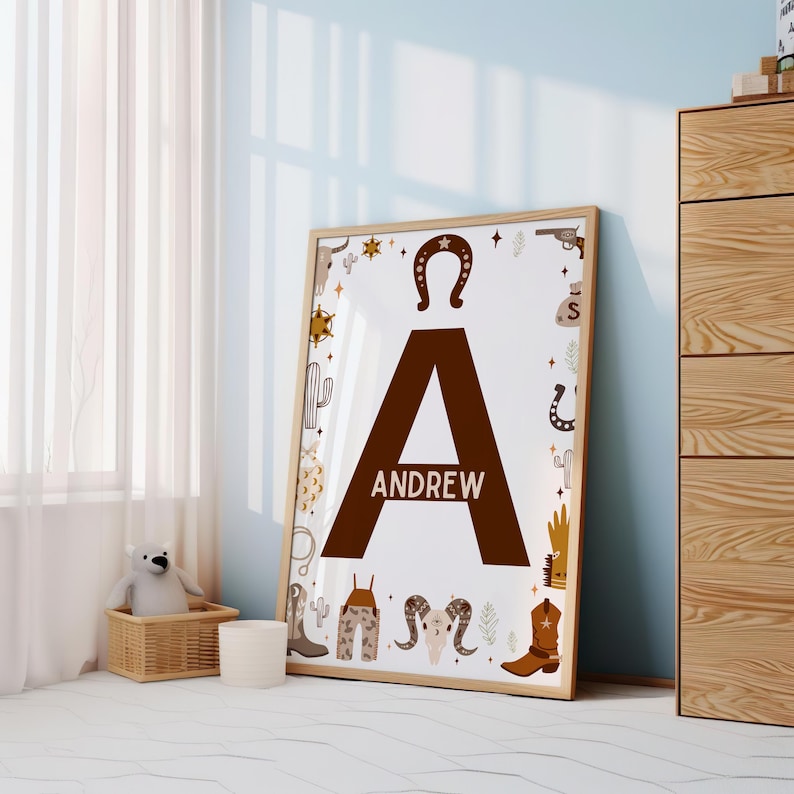 May include: A brown letter A with the name "ANDREW" printed below it. The letter is surrounded by a white border and a variety of western-themed illustrations, including cacti, horseshoes, stars, and cowboy boots.