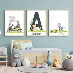 May include: Three framed prints with a golf theme. The first print features an elephant riding in a golf cart. The second print features a lion with the letter A and the name Andrew. The third print features a zebra with a golf club and ball.