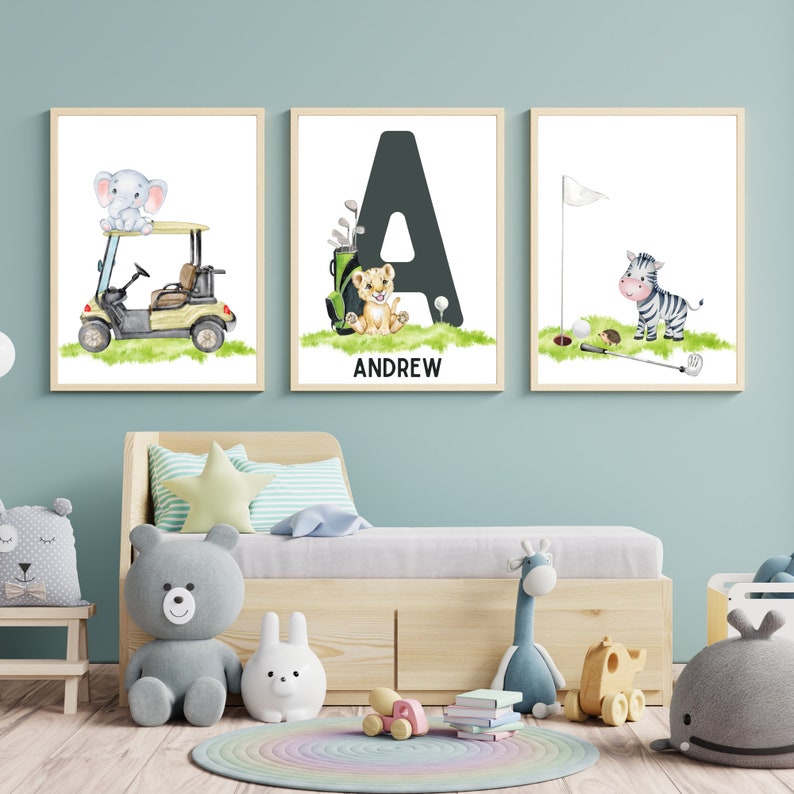 May include: Three framed prints with a golf theme. The first print features an elephant riding in a golf cart. The second print features a lion with the letter A and the name Andrew. The third print features a zebra with a golf club and ball.