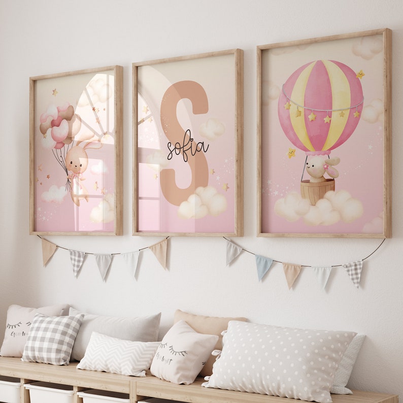 Pu&ograve; includere: Tre stampe incorniciate con uno schema di colori rosa e giallo. Le stampe mostrano un coniglio che tiene dei palloncini, una grande lettera S con il nome "sofia" scritto sotto, e un coniglio che cavalca una mongolfiera.