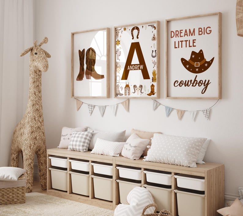 May include: Three framed prints with a western theme. The first print features a pair of brown cowboy boots. The second print features the letter A with the name Andrew below it. The third print features a cowboy hat with the text "Dream Big Little Cowboy".