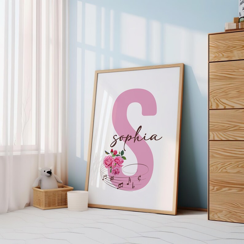 May include: A pink letter S with the name "Sophia" written in cursive below it. The letter is decorated with pink roses and musical notes.