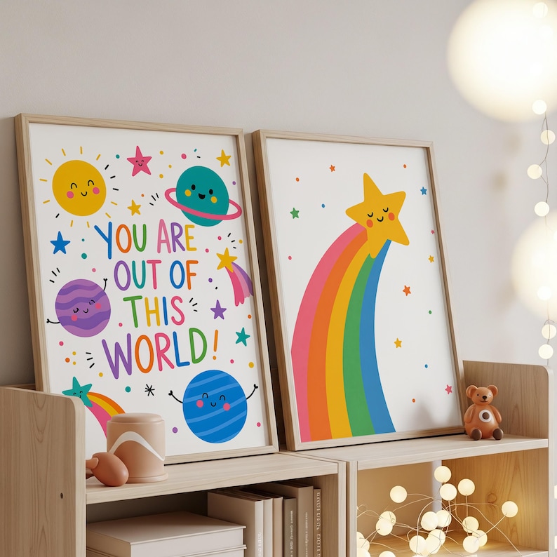 May include: Two framed art prints with a space theme. One features planets, stars, and the text "YOU ARE OUT OF THIS WORLD!". The other shows a smiling star with a rainbow. Both have a white background and wooden frames.