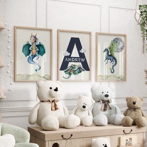 May include: Three framed prints with watercolor illustrations of dragons. The center print features the letter A with the name Andrew below it. The prints are displayed on a wall above a shelf with stuffed teddy bears.