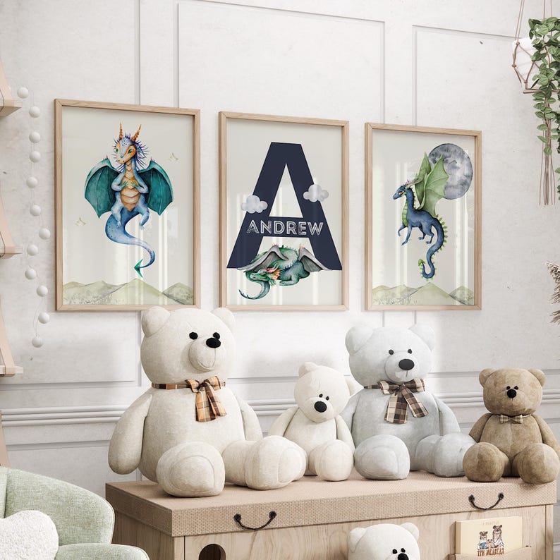 May include: Three framed prints with watercolor illustrations of dragons. The center print features the letter A with the name Andrew below it. The prints are displayed on a wall above a shelf with stuffed teddy bears.