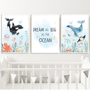 May include: A set of three framed watercolour prints with an ocean theme. One print shows a black and white orca, another has the text "Dream as Big as the Ocean", and the third depicts a blue whale. The prints include various sea creatures.