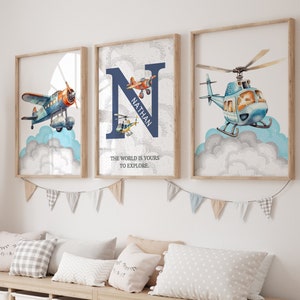 May include: Three framed prints with a blue and white watercolor design of airplanes and helicopters. The middle print features the letter N with the name Nathan and the text "The world is yours to explore."