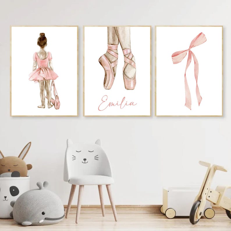 May include: Three watercolor prints featuring a ballerina, a pair of pink ballet shoes, and a pink ribbon. The ballerina is wearing a pink tutu and has her hair pulled back in a bun. The ballet shoes are tied with pink ribbons. The ribbon is tied in a bow. The prints are all framed in gold.