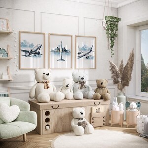 Puede incluir: Una escena de habitaci&oacute;n infantil con arte de aviones enmarcados, osos de peluche y un cofre de almacenamiento. La obra de arte representa pinturas de acuarela de aviones contra un cielo azul. Varios osos de peluche de diferentes tama&ntilde;os est&aacute;n colocados en un cofre de madera.