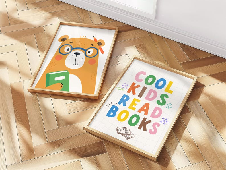 May include: Two framed art prints on a wooden floor. One features a cartoon bear wearing glasses and holding a book. The other print says "COOL KIDS READ BOOKS" in colorful letters, with an illustration of an open book.