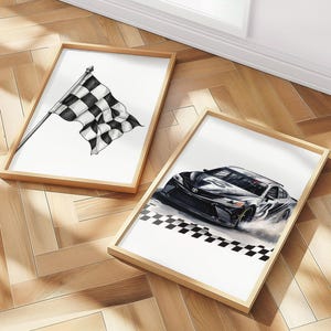 May include: Two framed art prints. One features a black and white checkered racing flag. The other depicts a black race car with a checkered finish line. Both prints have wooden frames and are on a wooden floor.