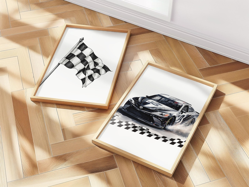 May include: Two framed art prints. One features a black and white checkered racing flag. The other depicts a black race car with a checkered finish line. Both prints have wooden frames and are on a wooden floor.
