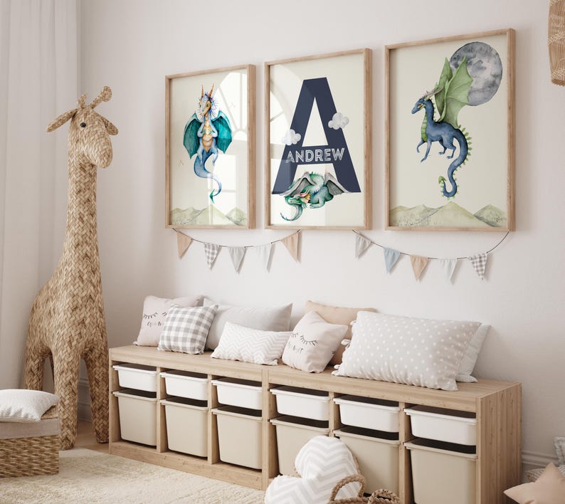 May include: Three framed watercolor prints featuring a blue dragon, the letter A with the name Andrew, and a blue dragon flying with a green moon. The prints are hanging on a white wall above a wooden bench with storage bins.