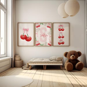 May include: Three framed prints with a cherry theme. The center print features a pink letter "S" with the name "sofia" written below it. The left print shows two red cherries with a pink bow. The right print shows a vertical row of three red cherries with pink bows.
