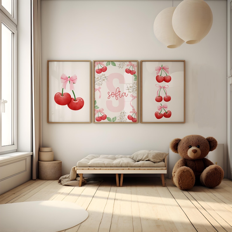 May include: Three framed prints with a cherry theme. The center print features a pink letter "S" with the name "sofia" written below it. The left print shows two red cherries with a pink bow. The right print shows a vertical row of three red cherries with pink bows.
