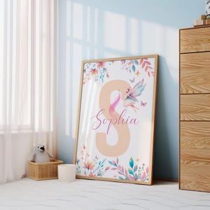 Peut inclure: Une impression aquarelle repr&eacute;sentant une f&eacute;e aux ailes roses et un motif floral. L'impression comprend le nom "Sophia" et une grande lettre "S" de couleur p&ecirc;che.