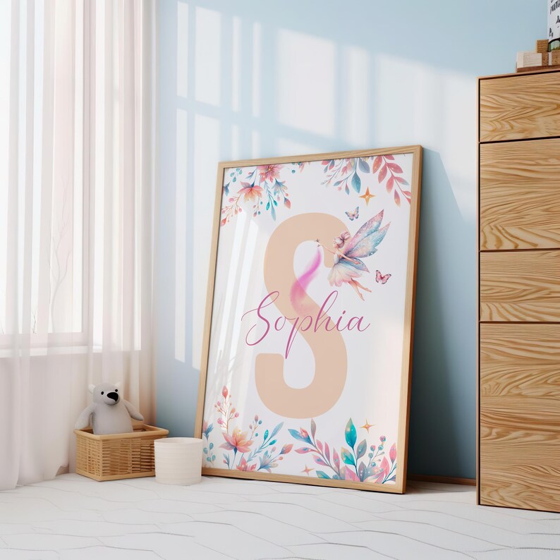 Peut inclure: Une impression aquarelle repr&eacute;sentant une f&eacute;e aux ailes roses et un motif floral. L'impression comprend le nom "Sophia" et une grande lettre "S" de couleur p&ecirc;che.