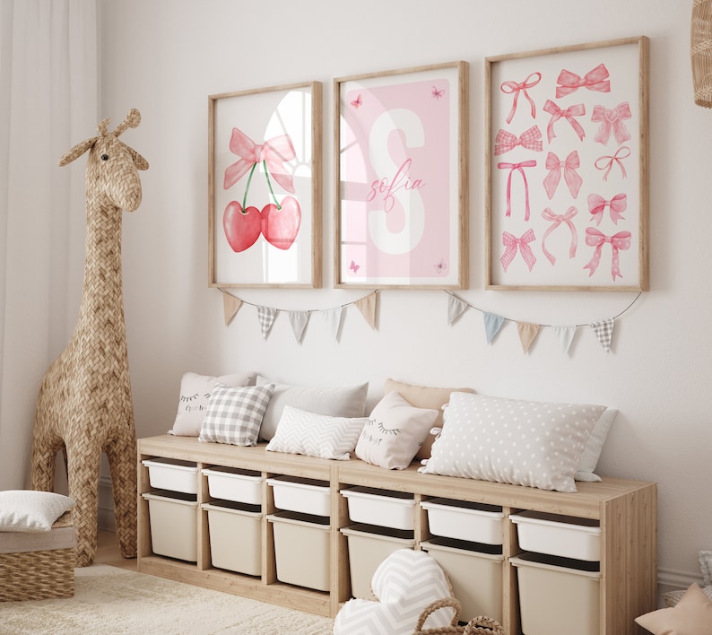 May include: Three framed prints with pink and white designs. The prints feature a cherry with a pink bow, the letter S with the name "Sofia" and a collection of pink bows.