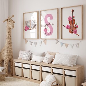 May include: Three framed prints with a pink floral theme. The first print features a book with musical notes and a pink rose. The second print features a pink letter "S" with the name "Sophia" and musical notes. The third print features a violin with pink roses.
