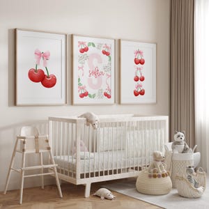 May include: Three framed prints with a cherry theme. The center print features a pink letter S with the name "Sofia" written below. The left print shows two red cherries with a pink bow. The right print shows a vertical row of red cherries with pink bows.