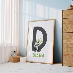 May include: A framed print with a black letter D and a panda bear illustration. The panda is holding a green bamboo stalk. The name "DIANA" is written in green below the letter.