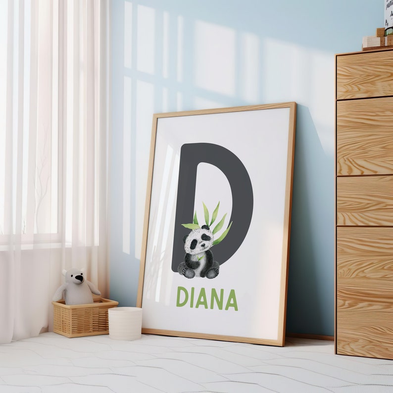 May include: A framed print with a black letter D and a panda bear illustration. The panda is holding a green bamboo stalk. The name "DIANA" is written in green below the letter.