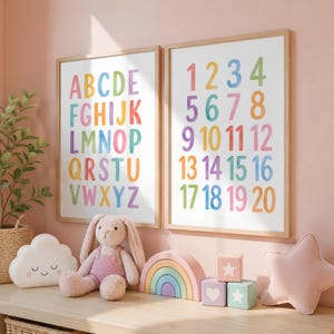 May include: Two framed educational prints with colorful letters and numbers. The alphabet print displays letters A-Z in rainbow hues. The number print shows numbers 1-20. A plush bunny, cloud pillow, rainbow stacker, and blocks are on the shelf.