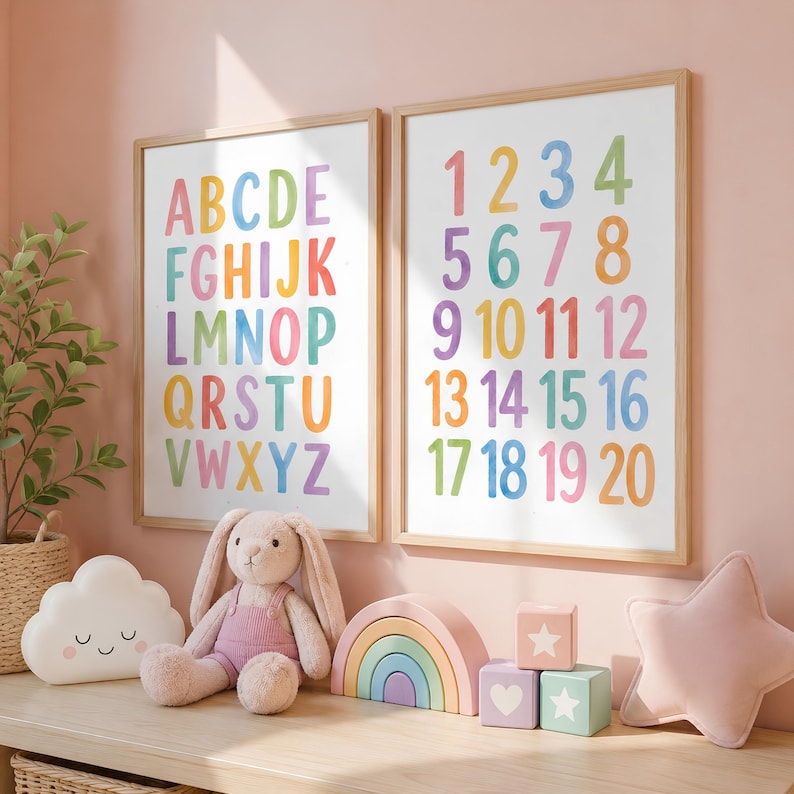 May include: Two framed educational prints with colorful letters and numbers. The alphabet print displays letters A-Z in rainbow hues. The number print shows numbers 1-20. A plush bunny, cloud pillow, rainbow stacker, and blocks are on the shelf.