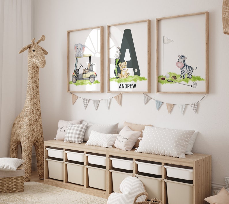 May include: Three framed prints with a safari animal theme. The prints feature a golf cart with an elephant, the letter A with a lion, and a zebra with a golf club. The letter A print has the name Andrew below it.