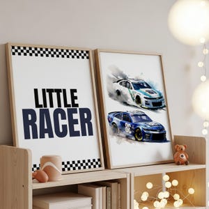 May include: Two framed prints on a wooden shelf. One print says "LITTLE RACER" in navy blue text with a checkered border. The other print features watercolor illustrations of two race cars, one white and one blue.