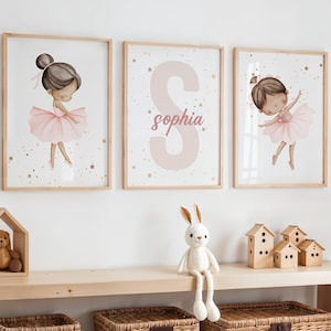 May include: Three framed wall art prints. Two prints feature watercolor illustrations of ballerinas in pink tutus. The third print displays the name "Sophia" in pink script over a large letter "S". The frames are light wood.