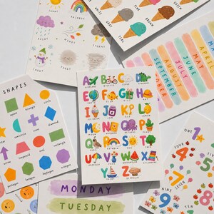 May include: A collection of colorful educational cards featuring shapes, the alphabet, numbers, weather, and months. The cards have illustrations of shapes, ice cream, and a rainbow. The word "Shapes" is at the top of one card.