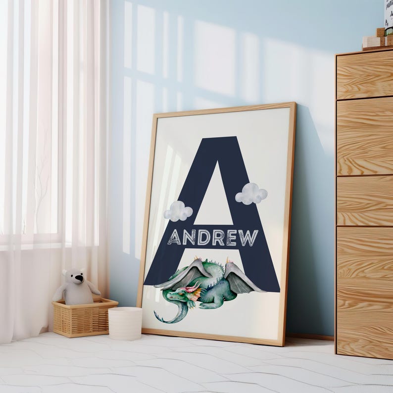 May include: A framed print with a large navy blue letter A and the name Andrew written in white. A green dragon with wings is lying below the letter. The print is on a white background.