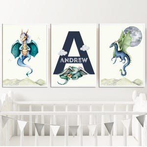 May include: Three watercolor prints featuring a blue dragon, the letter A in navy blue with the name Andrew, and a green dragon with a moon in the background.