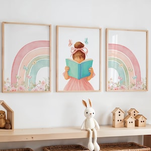 Pode incluir: Três impressões emolduradas em aquarela com um arco-íris e uma menina lendo um livro. As impressões do arco-íris apresentam cores pastel e borboletas. A impressão central mostra uma menina com um vestido rosa lendo um livro turquesa, com borboletas e um laço rosa.