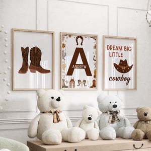 May include: Three framed prints with a western theme. The first print features a pair of brown cowboy boots. The second print features a large letter A with the name Andrew below it. The third print features a cowboy hat and the text "Dream Big Little Cowboy".