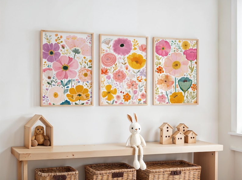 May include: Three framed floral art prints with watercolor flowers in pink, yellow, and purple hues. The prints are displayed above a wooden shelf with a teddy bear in a wooden house, a stuffed bunny, and decorative wooden houses.