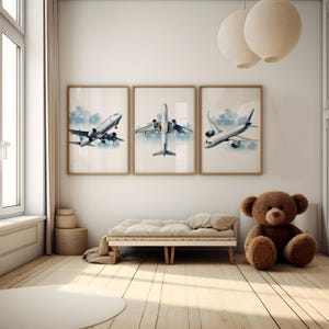 Puede incluir: Tres impresiones enmarcadas de aviones en una habitaci&oacute;n luminosa. Cada impresi&oacute;n presenta una vista diferente de un avi&oacute;n de pasajeros contra un cielo azul nublado. La habitaci&oacute;n incluye un peque&ntilde;o banco de madera, un oso de peluche y una alfombra redonda.