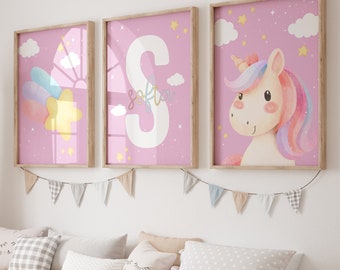 May include: Three framed prints with a pink background and white stars. The first print features a rainbow and a star. The second print features the letter S with the name "Sofia" written below. The third print features a cartoon unicorn with a rainbow mane and tail.