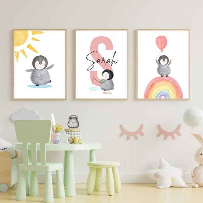 May include: Three watercolor prints featuring a penguin with a sun, a penguin fishing, and a penguin flying with a balloon over a rainbow. The middle print has the name "Sarah" written in pink.