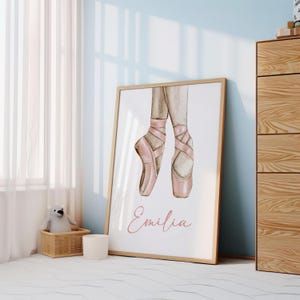 May include: A watercolor illustration of pink ballet shoes with the name "Emilia" written in pink script below.