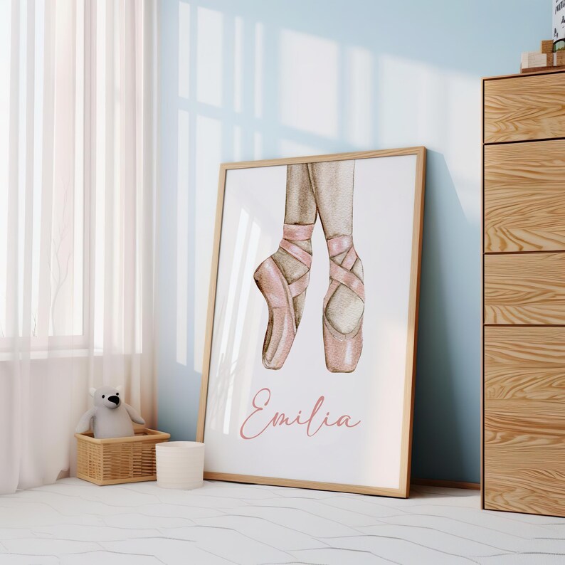 May include: A watercolor illustration of pink ballet shoes with the name "Emilia" written in pink script below.