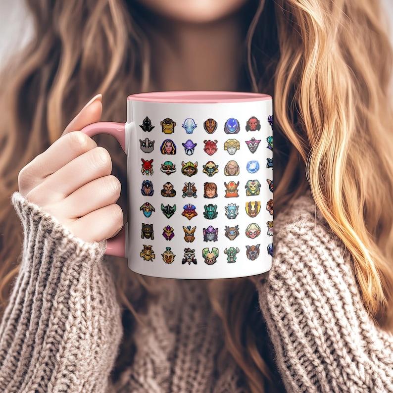 May include: White ceramic mug with a pink interior and handle, featuring a repeating pattern of colorful character portraits. The mug is held by a person wearing a beige sweater.