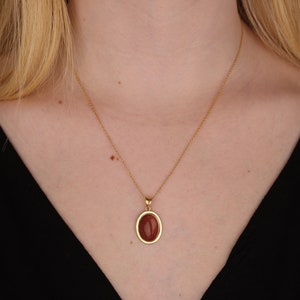 May include: A gold chain necklace with a brown oval pendant.