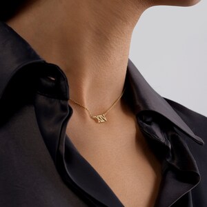 May include: A gold necklace with a Roman numeral pendant that reads "XV".