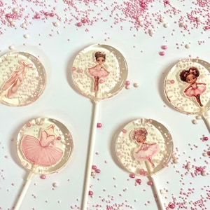 Könnte beinhalten: Fünf runde Lutscher mit verschiedenen Ballerina-Motiven. Die Lutscher befinden sich auf einem weißen Hintergrund mit rosa Streuseln.