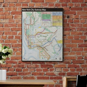 May include: A rectangular wall poster featuring a New York City Subway Map with a black border and header text. The map displays intricate colored transit lines, station markers, and a detailed legend grid against a white background.